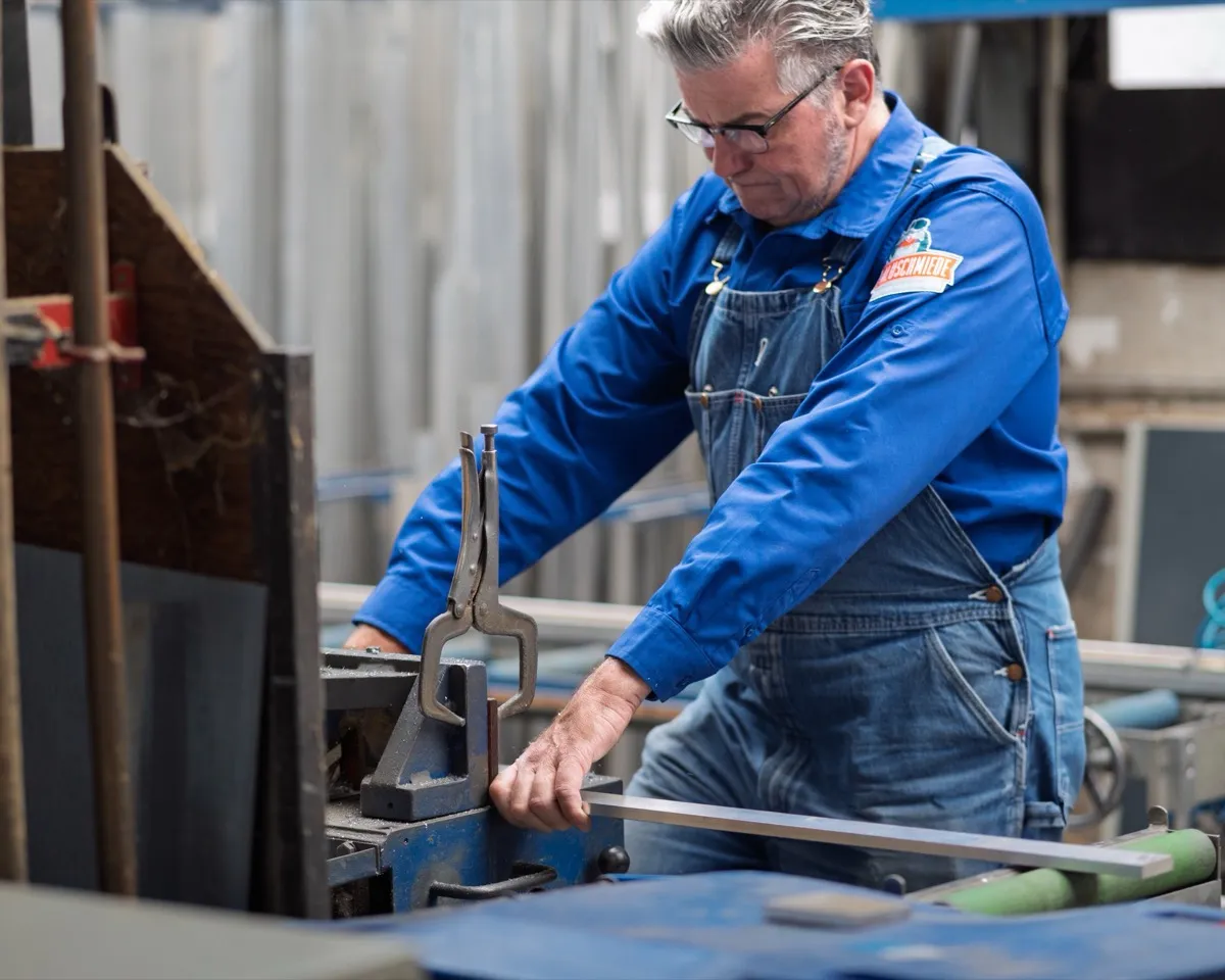 Axel Graupe führt in der Werkstatt ein Aluminiumprofil durch eine Maschine