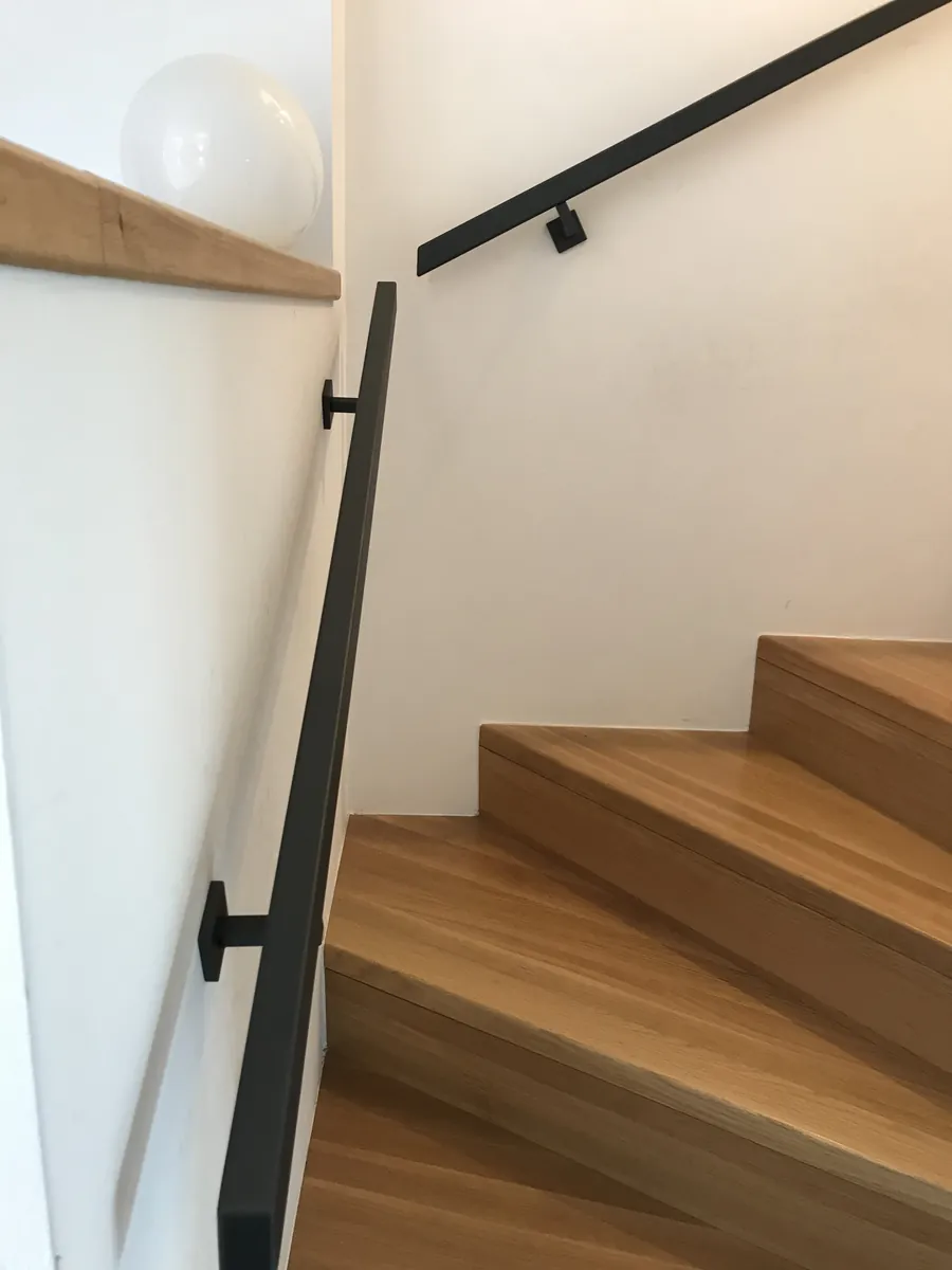Schwarzer Handlauf an einer Holztreppe im Haus