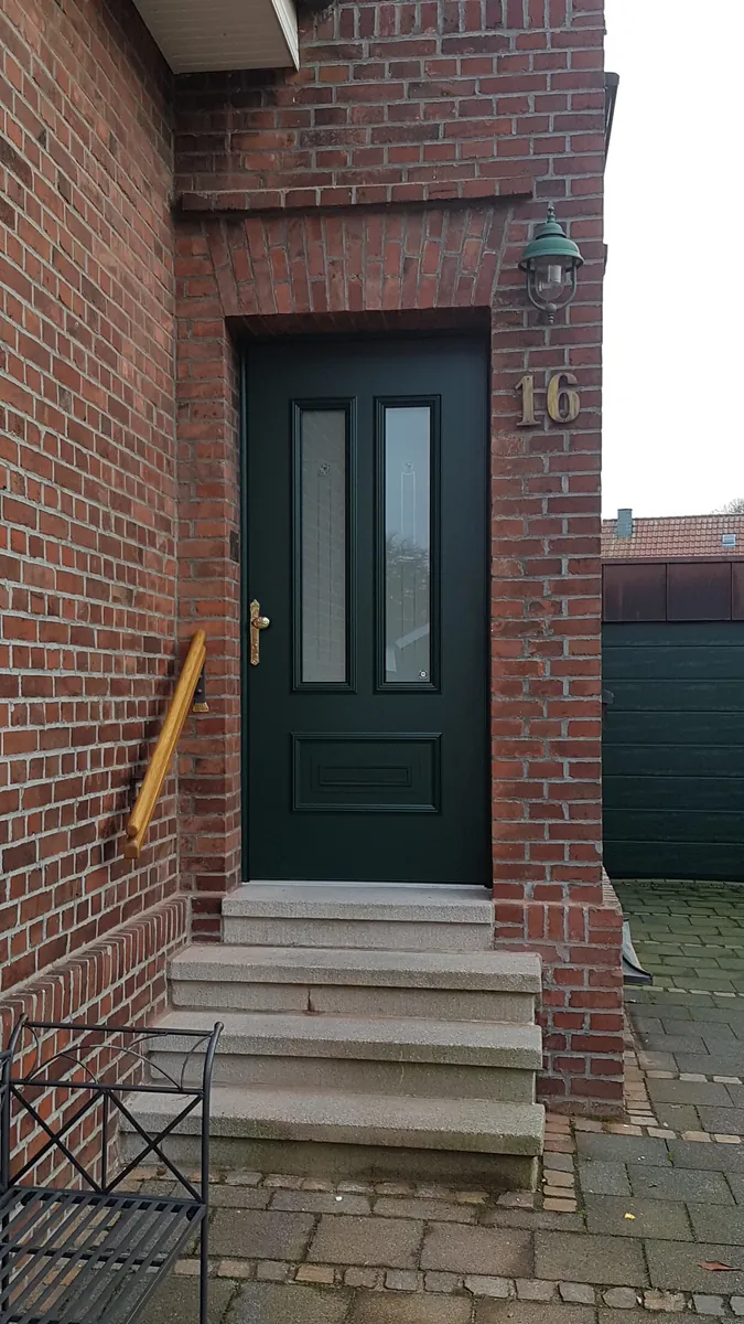 Dunkelgrüne Haustür mit Glaseinsätzen in einem Klinkereingang