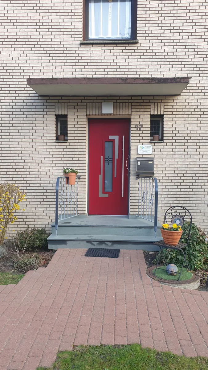 Rote Haustür mit Vordach und Handläufen