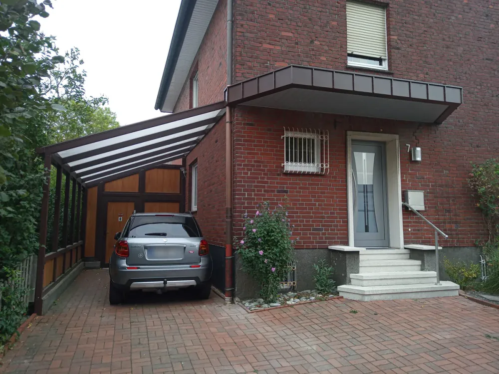 Kastenvordach und Carport mit Lichtplatten an einem Klinkerhaus