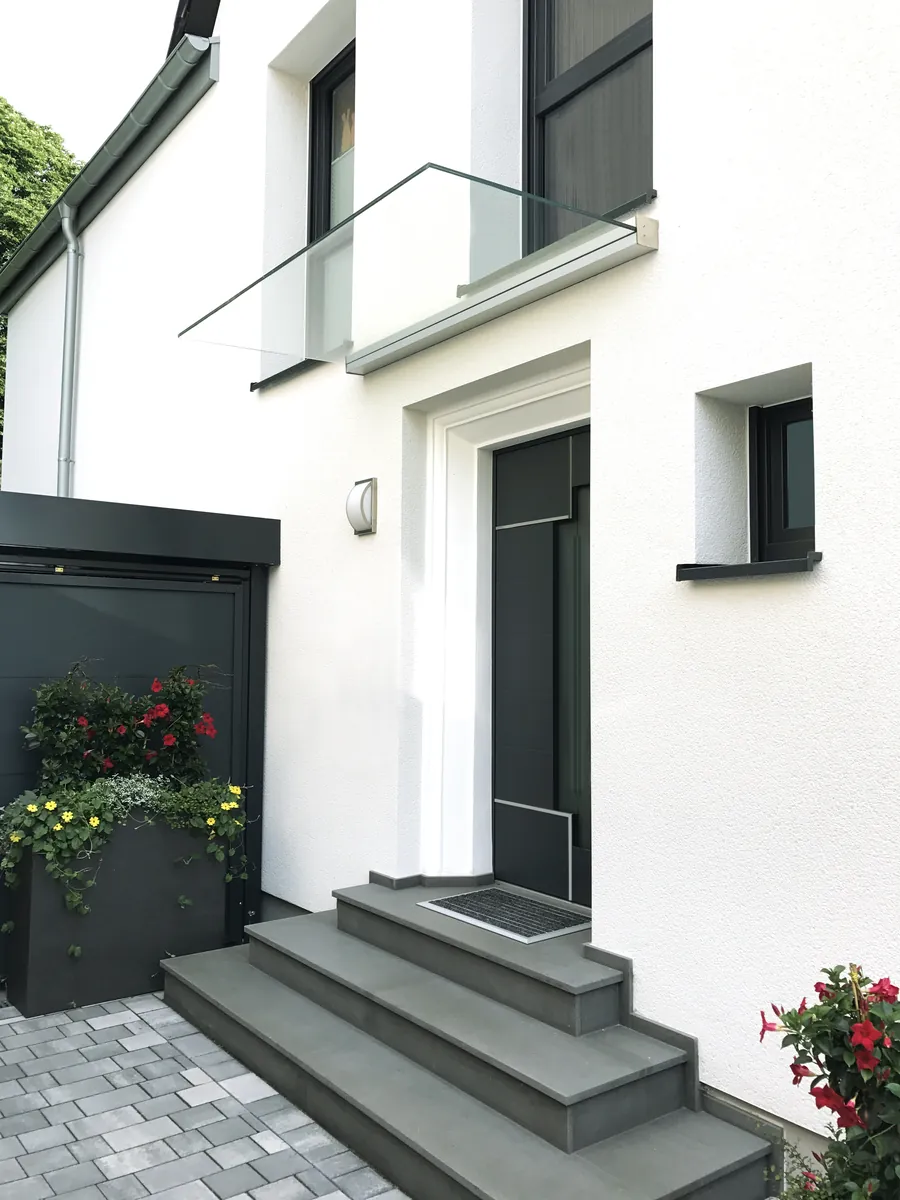 Glasvordach an einem weißen Neubau