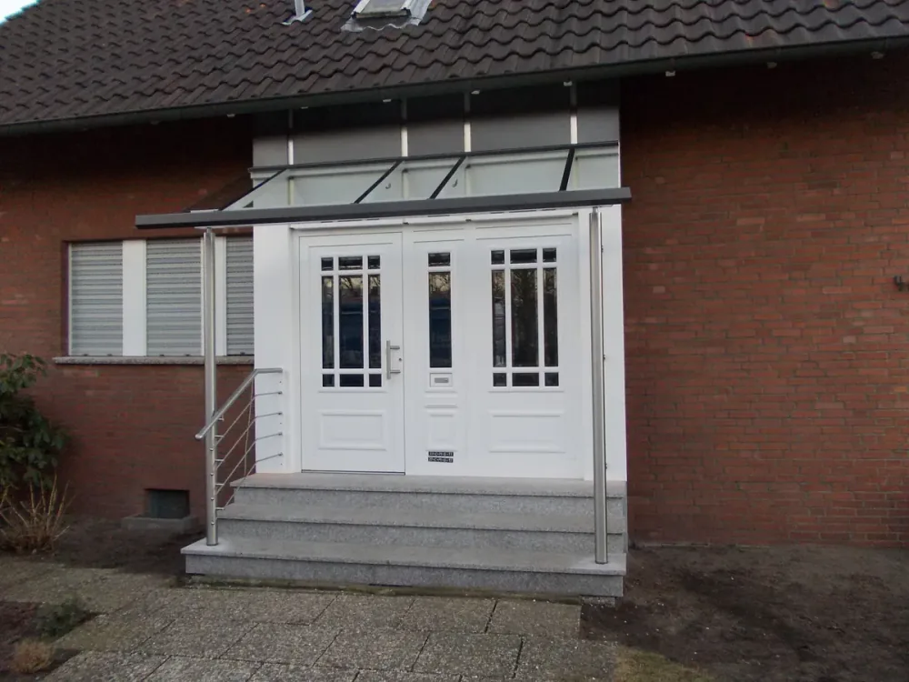 Glasvordach mit Sprossen über einer zweiflügeligen Haustür